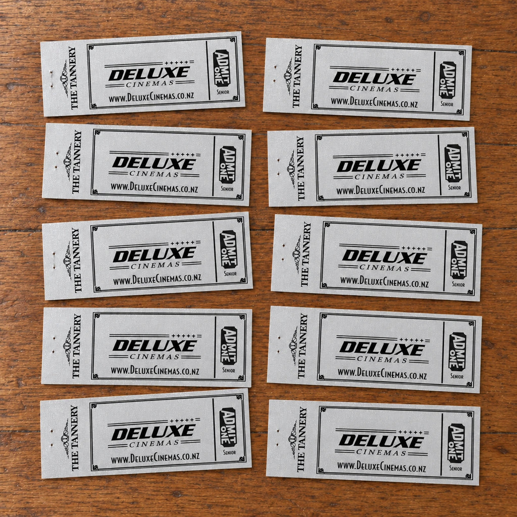 Ten older silver Deluxe Cinemas Senior vouchers laid naturally on a wooden table