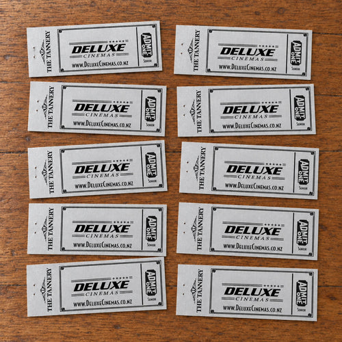 Ten older silver Deluxe Cinemas Senior vouchers laid naturally on a wooden table